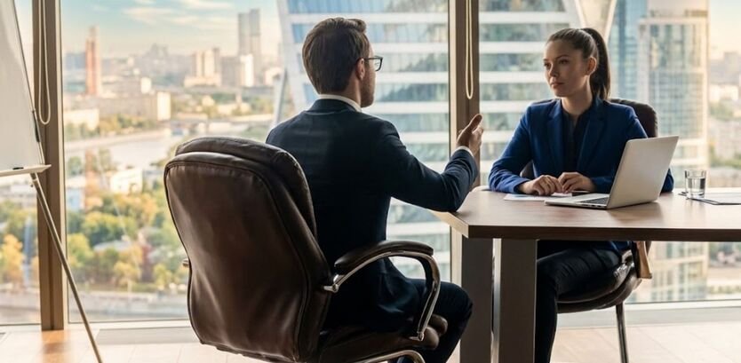 A professional job interview taking place in a modern high-rise office with a cityscape view, showing effective communication for confidence building.